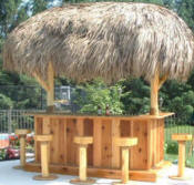 A picture of a tiki bar with thatched roof and bar stools.